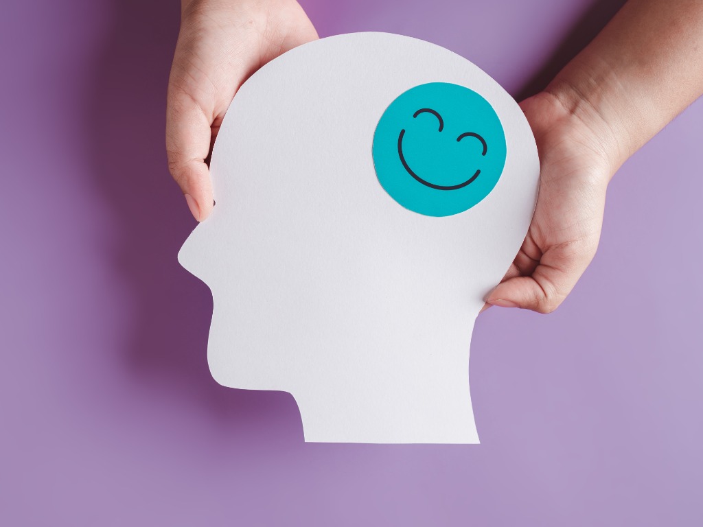 Manos sosteniendo la cara sonriente en el corte de papel cerebral, emoción sonriente feliz y hormonas del estado de ánimo relajantes, sensación de energía completa, químicos cerebrales, concepto de salud mental positivo